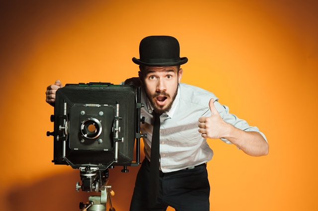 A man with a vintage camera giving a thumbs-up.