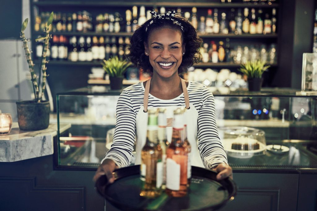 Friendly African restaurant server holding a tray of drinks